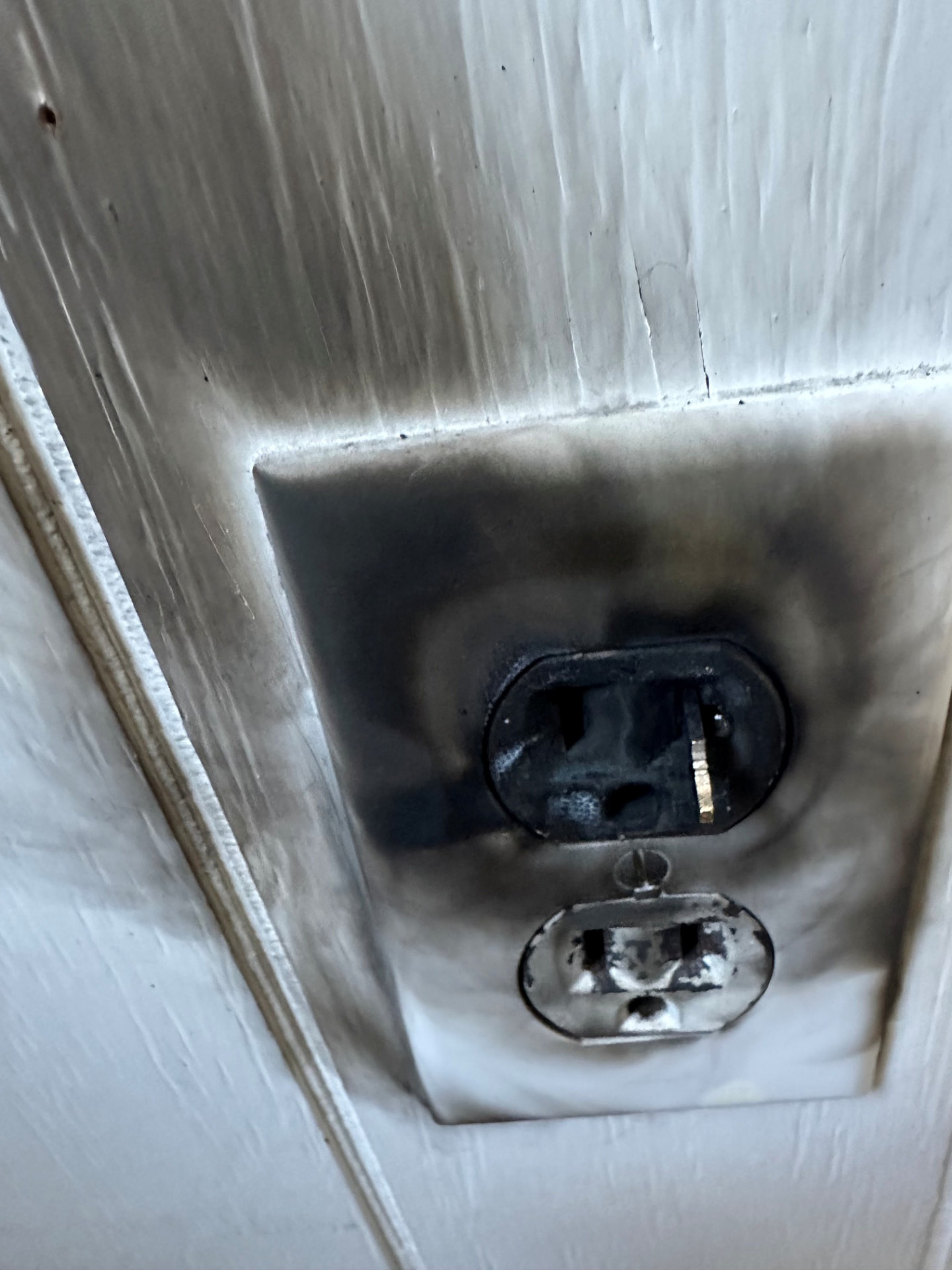 Boston Light & Power electrician replacing a scorched electrical outlet on a wall in Boston, MA.