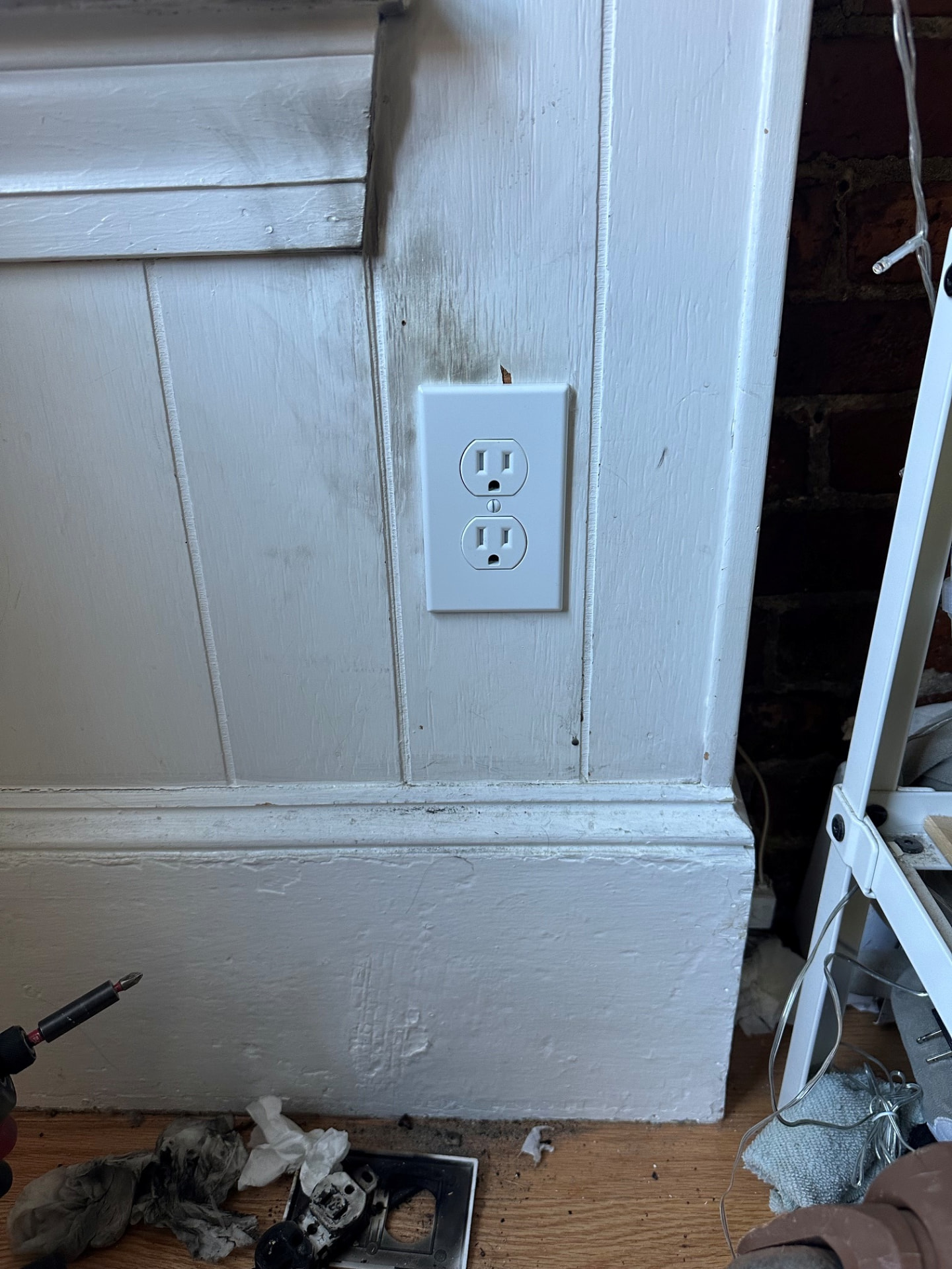 Boston Light & Power electrician installing a new electrical outlet in finished wall paneling in Hingham, MA.