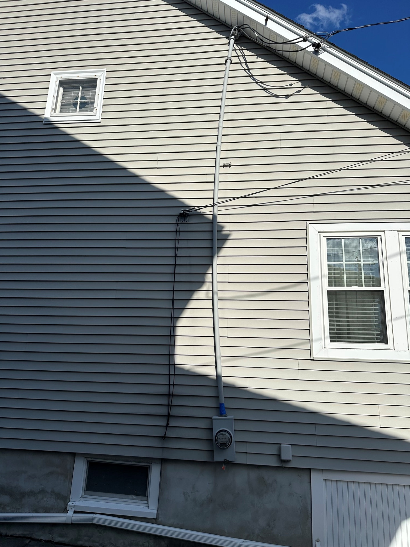 Boston Light & Power electrician upgrading an overhead service entrance with new conduit and meter on a gable end in Braintree, MA.