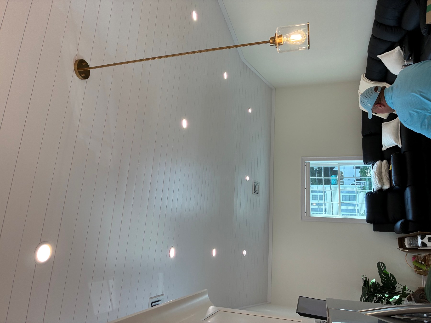 Boston Light & Power electrician installing recessed lighting and a brass pendant on a vaulted living room ceiling in Quincy, MA.