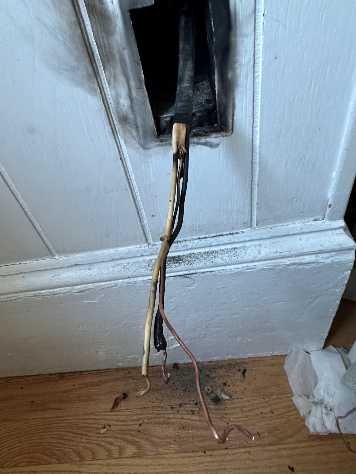 Boston Light & Power electrician removing heat-damaged wiring from a wall box during a repair in Milton, MA.
